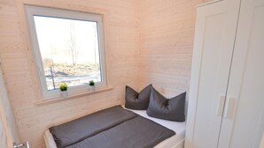 A small, single-bed room with a window, a wardrobe, and a small plant on the windowsill. - Holiday Home Near Bukowo Lake and Beaches (Darlowo)