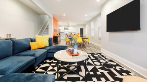 Un salon moderne avec un canapé bleu, une table basse ronde et un tapis à motifs.