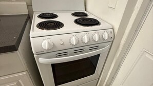 Una estufa de gas blanca con cuatro hornillas y una puerta de horno.