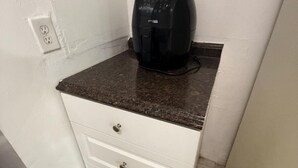 Una pequeña kitchenette con una encimera, una cafetera y una unidad de cajones.