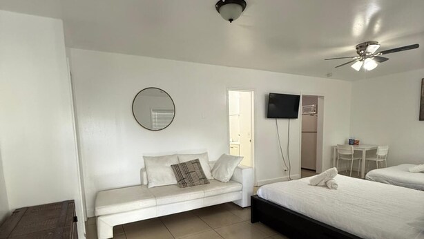 Un dormitorio moderno con cama, sofá, televisor y ventilador de techo.