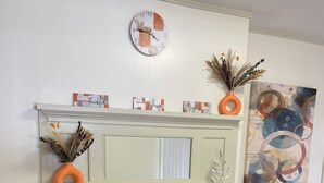 A fireplace with decorative items, a clock, and artwork on the wall.