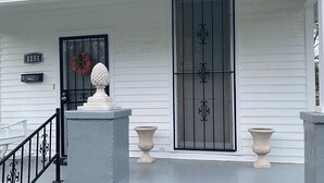 A white house with a black front door, a mailbox, and a wreath.