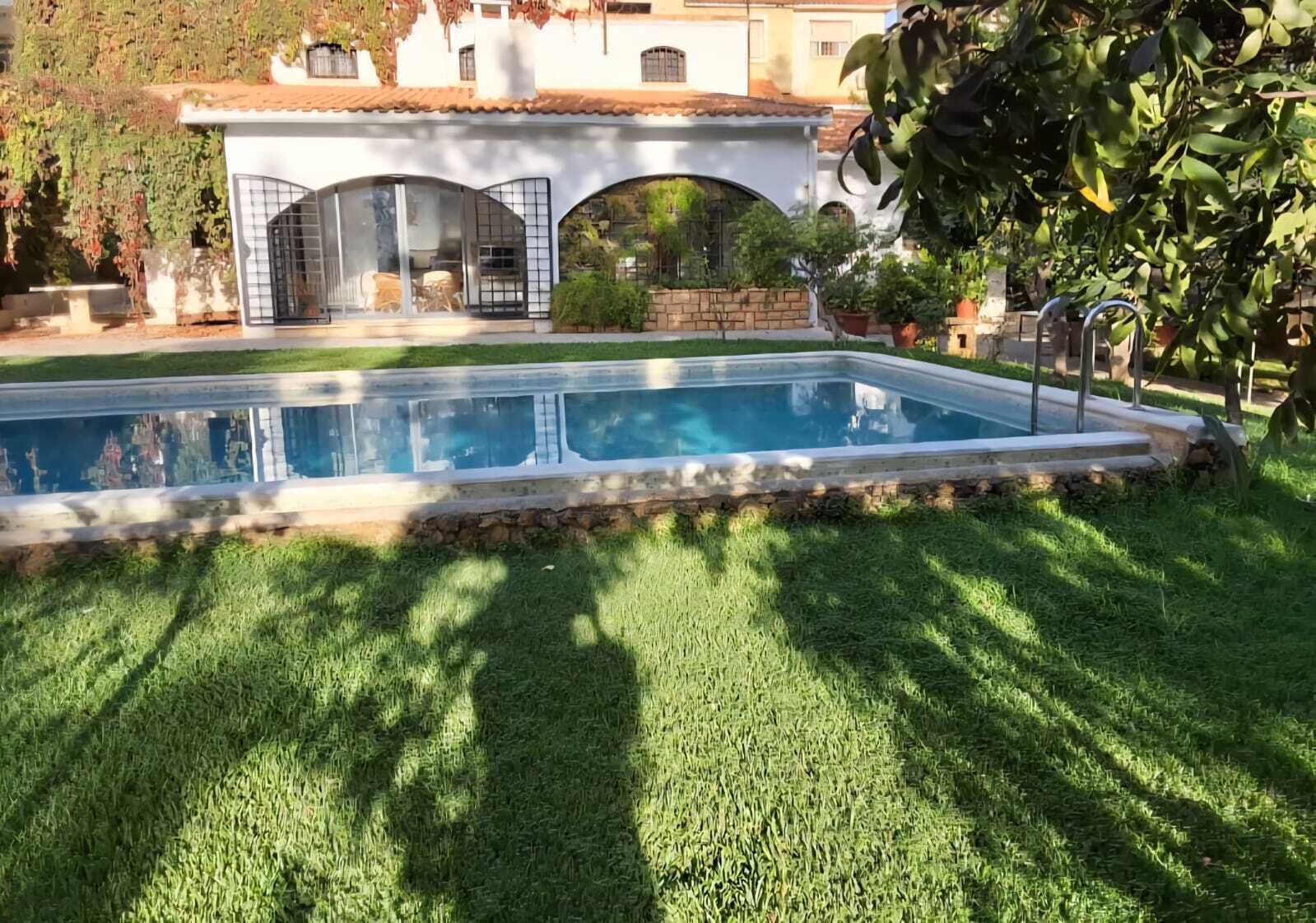 Une piscine bordée de pierres, entourée d’une pelouse bien entretenue.