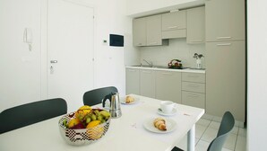 A small, clean room with a dining table set for breakfast, a bowl of fruit, and a croissant on the table. - Apartment in Pietra Ligure With Garden (Pietra Ligure)