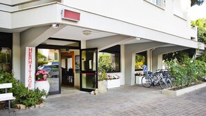 A hotel entrance with a covered walkway, a sign reading "HERMITAGE," and bicycles parked outside. - Apartment in Pietra Ligure With Garden (Pietra Ligure)