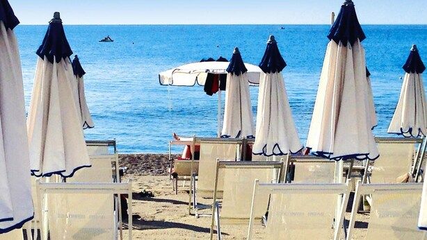 Beach chairs and umbrellas arranged on the sand, facing the sea. - Apartment in Pietra Ligure With Garden (Pietra Ligure)