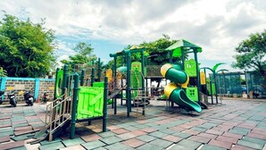 A playground with green and yellow play structures, surrounded by a paved area and trees. - Studio Unit W/ Balcony•Sea & City View (Lapu-Lapu)