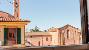 Vista de una iglesia con un campanario y un edificio con contraventanas verdes.