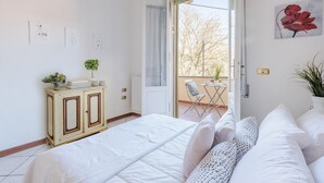 Un dormitorio con cama, una pequeña mesa con sillas, un armario y vistas al exterior.