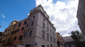 Un immeuble à étages doté d’un style architectural classique, caractérisé par une variété de modèles de fenêtres et une entrée d’angle bien visible.