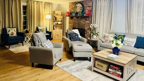Una sala de estar acogedora con chimenea, dos sofás, una mesa de centro y una estantería.