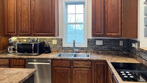 A kitchen with wooden cabinets, a built-in microwave, a dishwasher, a sink, and a stovetop.