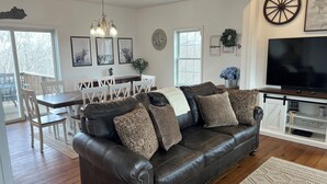 A living room with a leather sofa, dining table, chairs, and a TV.