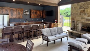 A modern kitchen with wooden cabinets, a bar area, and a stone fireplace.