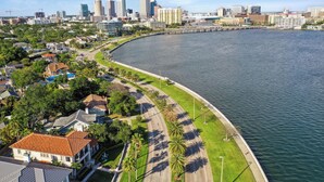 Un paisaje urbano costero con un paseo marítimo curvo, modernos edificios de gran altura y zonas residenciales con casas.