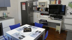 A compact kitchen with a refrigerator, microwave, and a small dining table with chairs. - The Dream Fisherman: a cozy nest in the center of town  (Pescara)