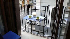 A balcony with a table set for two, a bicycle parked outside, and a building with a storefront in the background. - The Dream Fisherman: a cozy nest in the center of town  (Pescara)