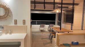 Une chambre d’hôtel moderne avec balcon, une table à manger en bois et un grand miroir.