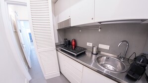 A modern kitchen with white cabinets, a stainless steel sink, a coffee maker, and a kettle. - Vatican Mascherino suite (MAS-2) (Roma)