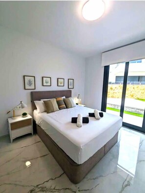 Un dormitorio moderno con una cama grande, una mesita de noche y una ventana con vistas.