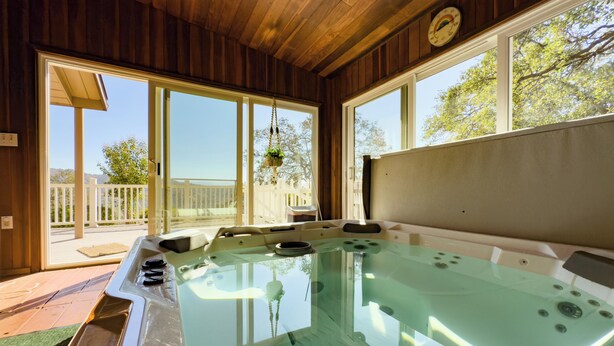 Een hottub met houten plafond en grote ramen.