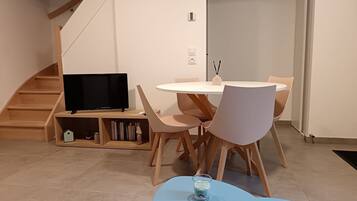 Ein moderner Essbereich mit einem runden Tisch, Holzstühlen und einem Fernseher auf einem Holzgestell.