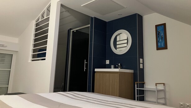 A modern bedroom with a bed, a wooden cabinet, a circular mirror, and a small ladder.