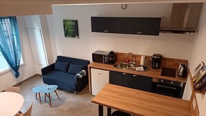 A compact living space with a kitchenette, a sofa, a dining table, and a small coffee table.