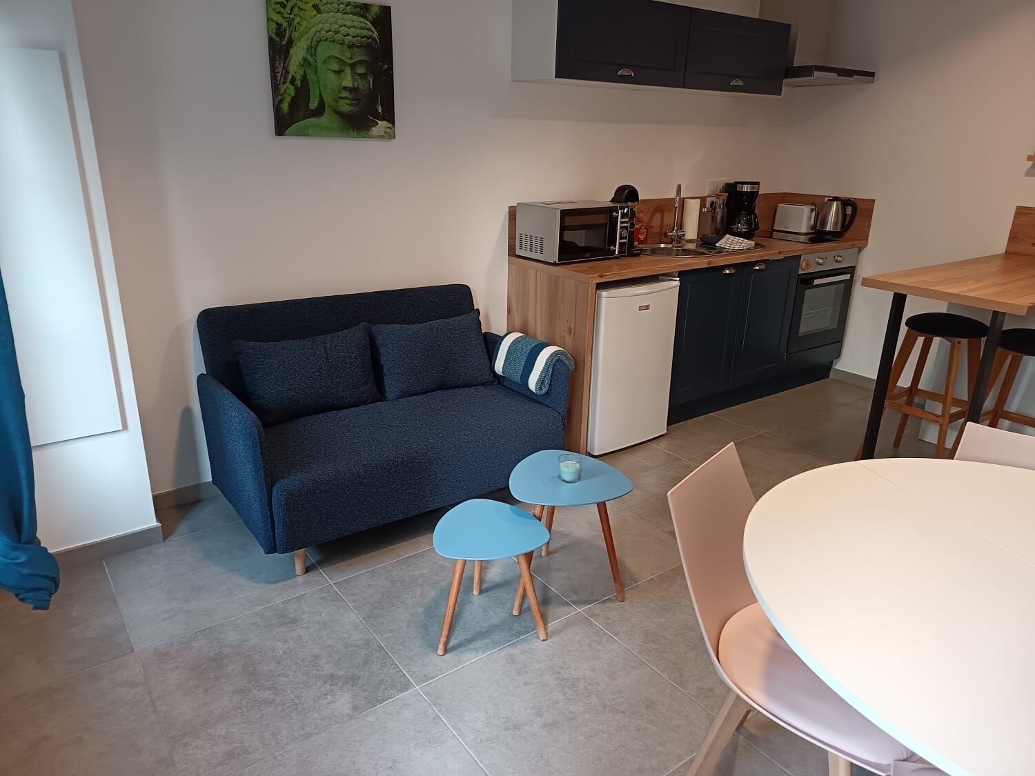 Un espace de vie compact comprenant un canapé, une petite table, une table à manger et un coin cuisine.