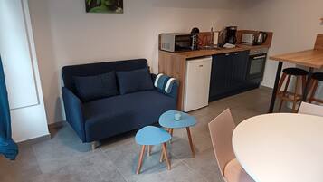 Un espace de vie compact comprenant un canapé, une petite table, une table à manger et un coin cuisine.