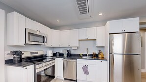 A modern kitchen with white cabinets, stainless steel appliances, and a black countertop. - Five75 Lux PROV - Suite 3  (Providence)