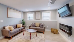 A living room with two sofas, a coffee table, a TV, and a fireplace. - Five75 Lux PROV - Suite 3  (Providence)