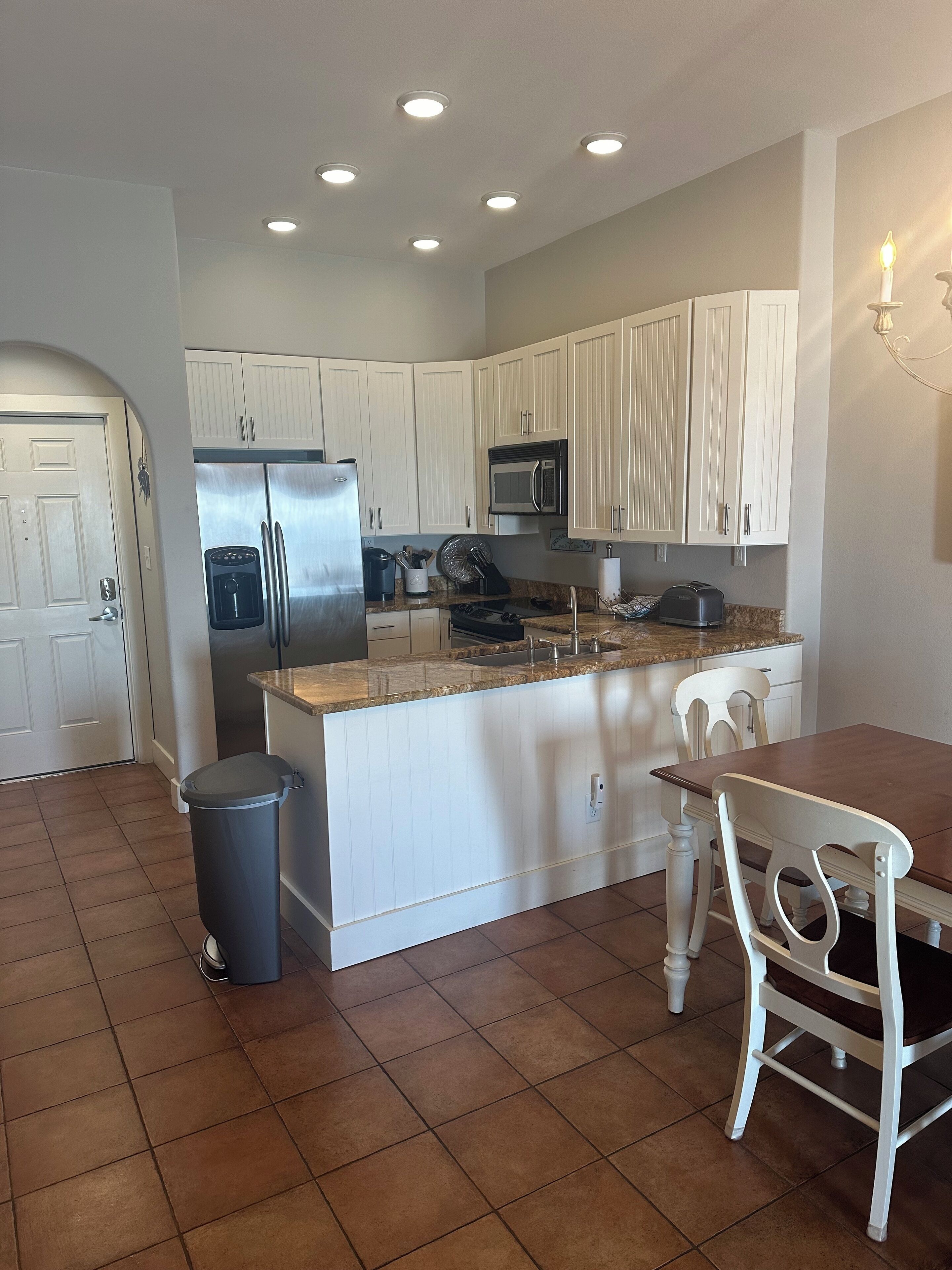 A kitchen with white cabinets, a stainless steel refrigerator, a microwave, and a sink.