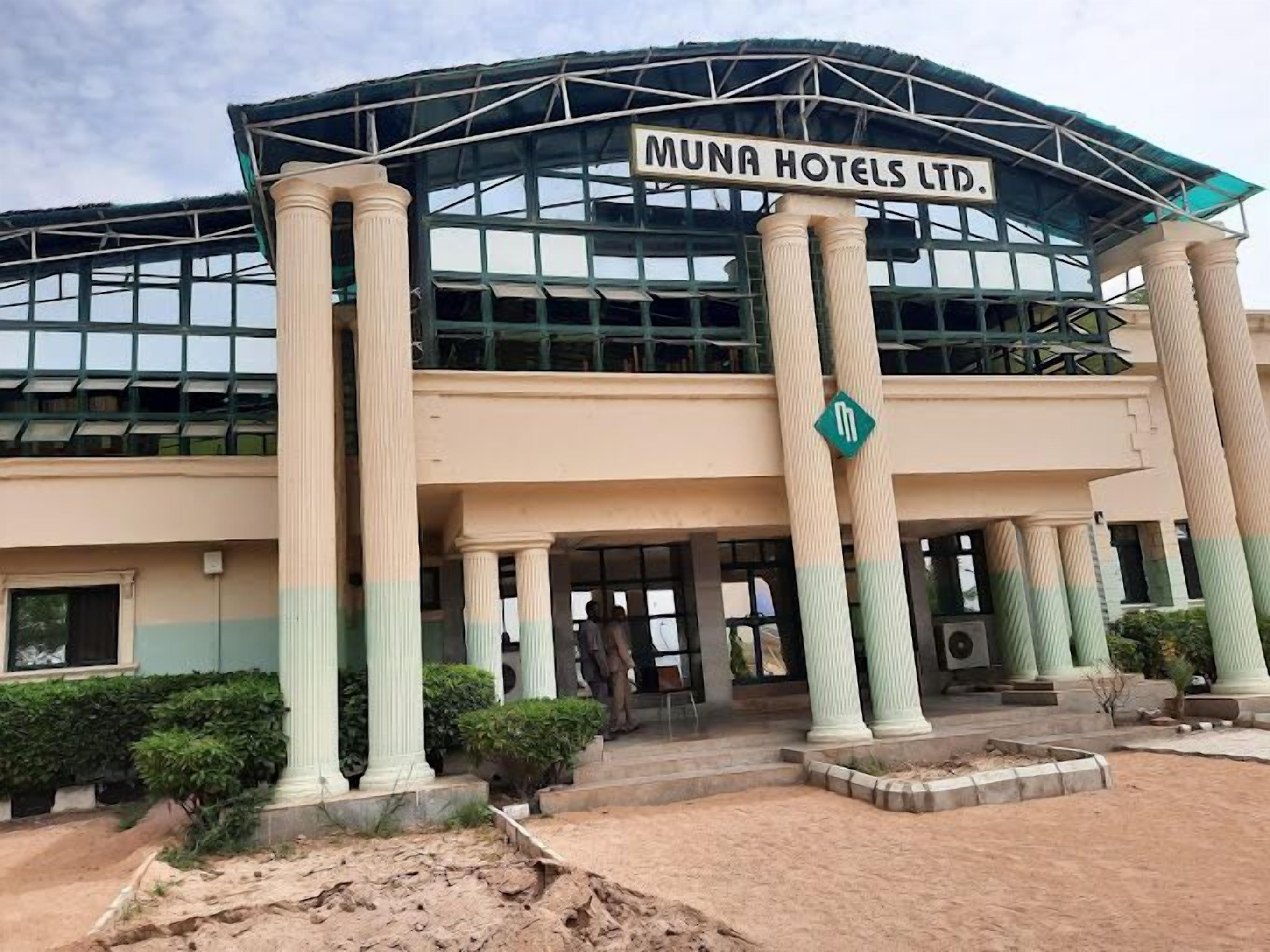 A hotel with a modern design, featuring large columns and a prominent sign reading "MUNA HOTELS LTD."