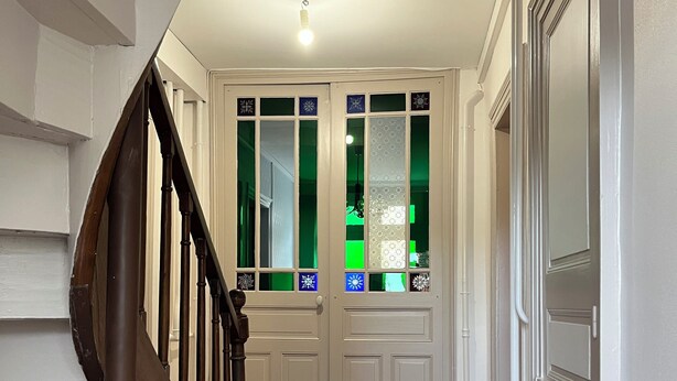 Een trap die leidt naar een paar dubbele deuren met glaspanelen en decoratieve details.