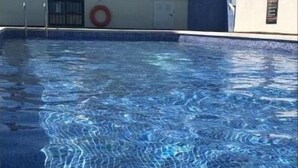 En swimmingpool med kristallklart blått vatten, en livboj och en satellitantenn på taket.