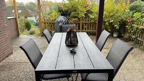 A wooden table with chairs, a black lantern, and a garden in the background. - House at the Schafwedel - Stelle (Stelle)