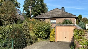 A residential house with a paved driveway, a wooden gate, and a brick wall. - House at the Schafwedel - Stelle (Stelle)