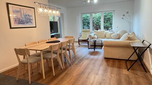 A modern living room with a wooden dining table, a sofa, and a TV. - House at the Schafwedel - Stelle (Stelle)