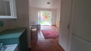 Ein schmaler Korridor mit Fliesenboden führt zu einem Essbereich mit einem roten Teppich.