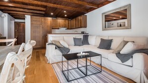 Una sala moderna con un sofá blanco, una mesa de centro negra y vigas de madera en el techo.
