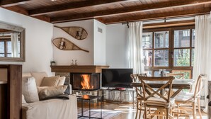 Una sala de estar acogedora con chimenea, muebles de madera y ventanas amplias.