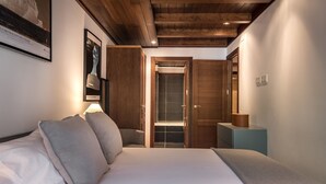 Un dormitorio con cama, almohadas, mesita de noche, lámpara y armario.