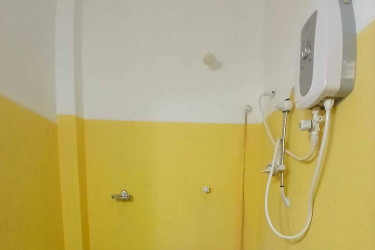 A small bathroom with a toilet, a shower unit, and a stone-tiled floor.