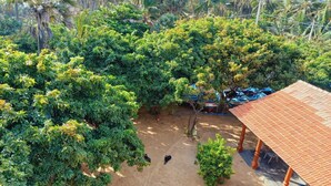 An aerial view of a property with dense greenery, a covered outdoor area, and parked vehicles. - Alankuda Dolphin Village (Norocholai)