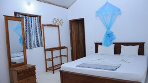 A bedroom with a wooden bed, a wooden dresser, a mirror, and a blue canopy. - Alankuda Dolphin Village (Norocholai)