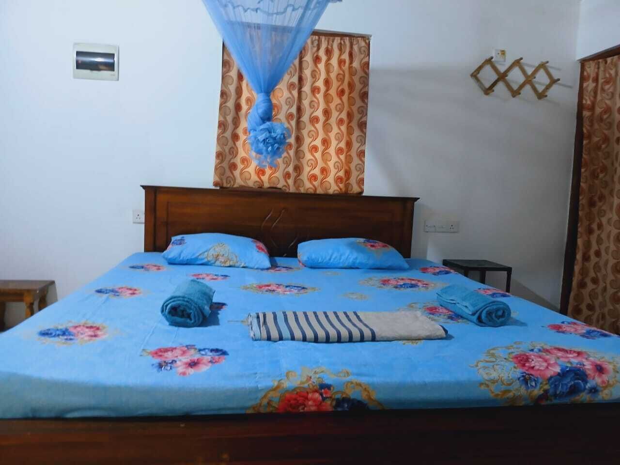 A bed with a floral bedspread, a wooden headboard, and a small bedside table.