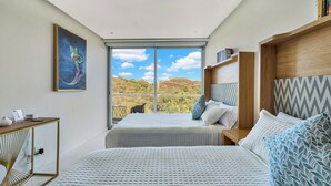 A bedroom with two beds, a view of the outdoors, a painting, and a bookshelf. - Relax in Bolongo 3BR Ocean View Condo Punta de Mita, AC and WiFi included (Corral del Risco)