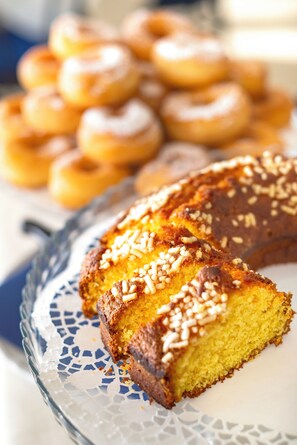 A slice of cake with a golden-brown crust and a yellow interior, garnished with nuts, on a decorative glass plate. - Hotel Grand Meeting (Rimini)